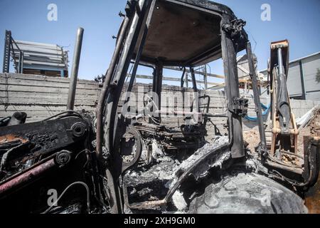 Nablus, Palestina. 12 luglio 2024. Un palestinese ispeziona un bulldozer bruciato dai coloni ebrei dell'insediamento israeliano di Homesh. Un gruppo di coloni mascherati attaccò negozi e case nel villaggio di Bazaria, a nord della città di Nablus in Cisgiordania. Credito: SOPA Images Limited/Alamy Live News Foto Stock