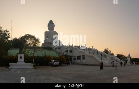 Una foto della grande statua del grande Buddha di Phuket, al tramonto, con i turisti intorno. Foto Stock