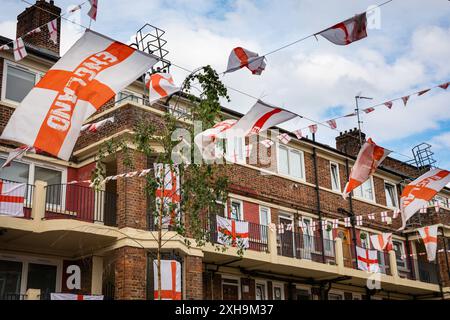Bermondsey, Londra, 12 luglio 2024. La tenuta Kirby di Bermondsey, nota per le sue colorate bandiere per le partite di calcio dell'Inghilterra, è ancora una volta decorata con diverse centinaia di bandiere in tutta la tenuta patriottica, così come il murale recentemente inaugurato di Eberechi Eze e altri pittoreschi murales nei grouds, in vista della finale di domenica tra Inghilterra e Spagna dei Campionati europei di calcio. Crediti: Imageplotter/Alamy Live News Foto Stock