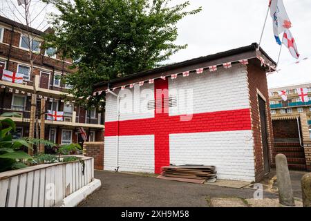 Bermondsey, Londra, 12 luglio 2024. Anche il deposito ha subito un restyling, con una bandiera inglese. Kirby Estate a Bermondsey, conosciuta per le sue colorate bandiere per le partite di calcio dell'Inghilterra, è ancora una volta addobbata in diverse centinaia di bandiere in tutta la tenuta patriottica, così come il murale recentemente inaugurato di Eberechi Eze e altri pittoreschi murales nei grouds, in vista della finale di domenica tra Inghilterra e Spagna dei Campionati europei di calcio. Crediti: Imageplotter/Alamy Live News Foto Stock