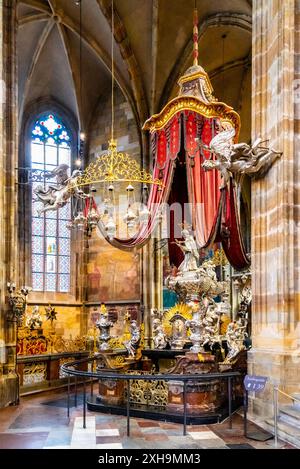 Il baldacchino ornato di St. La tomba d'argento di Giovanni di Nepomuk, con i suoi tendaggi rossi e i dettagli intricati, si trova all'interno del grandioso interno della cattedrale di San Vito. Praga, Cechia Foto Stock