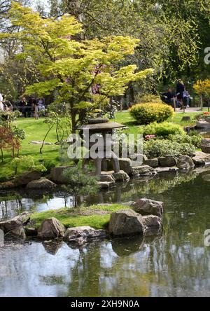 Riflessi di una lampada di pietra giapponese, in acqua ai Giardini di Kyoto, Holland Park, Londra. Foto Stock