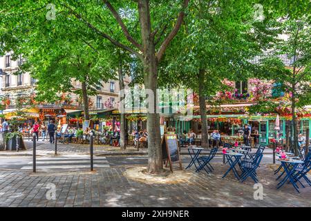 Angolo alberato di Rue du Montparnasse con vista sul Café Odessa e il Cafe de la Place - Parigi 75014, Francia. Foto Stock