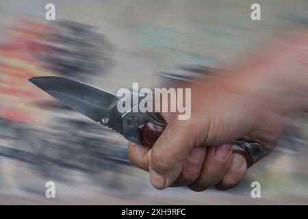 L'immagine mostra il pugno di un uomo che maneggia un coltello. In Germania gli attacchi con coltello stanno aumentando drasticamente. Foto Stock