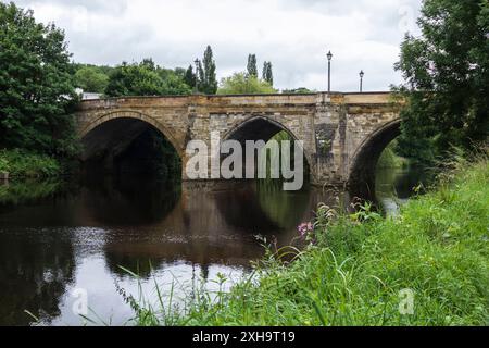 Una vista panoramica del fiume Tees a Yarm che mostra il ponte stradale e le rive alberate del fiume con riflessi sull'acqua Foto Stock