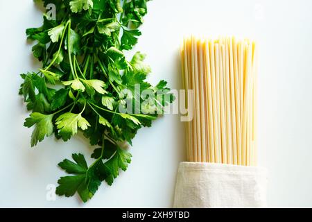 Prezzemolo italiano e spaghetti su sfondo bianco Foto Stock