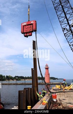 Equipaggi di Roen Salvage Co., di Sturgeon Bay, Wisc. Utilizzare un martello vibrante per inserire pile di metallo nel basamento sul frangiflutti sud di Algoma. Il calcestruzzo incapsula il muro, sostituendo la struttura vecchia di 90 anni. Il progetto è gestito dal U.S. Army Corps of Engineers, Chicago District e sarà completato nel giugno 2026. Foto Stock