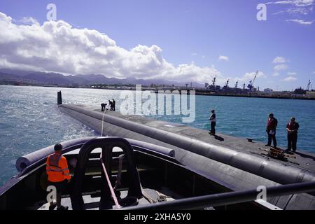 I marinai con il sottomarino d'attacco rapido classe Virginia USS Minnesota (SSN 783) si preparano a rilasciare una linea di traino per tornare al rimorchiatore ASD Neil Abercrombie, mentre iniziano le prove in mare, Pearl Harbor, Hawaii, 20 giugno 2024. Il Minnesota è entrato in un attracco esteso Selected Restricted Availability (EDSRA) presso Pearl Harbor Naval Shipyard and Intermediate Maintenance Facility (PHNSY & IMF) quasi 25 mesi fa. Durante il periodo di manutenzione, il cantiere navale e l'equipaggio hanno eseguito il brillamento e il rivestimento dei serbatoi, la conservazione dello scafo, la propulsione e le riparazioni del sistema navale, gli aggiornamenti di modernizzazione e apportato miglioramenti ai sistemi meccanici e Foto Stock