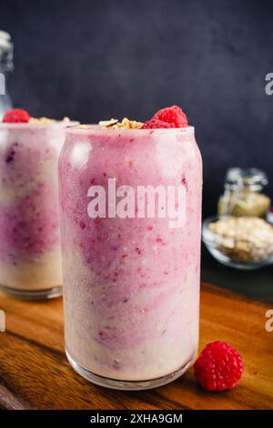 Frullati di lamponi di banana in bicchieri Tumbler: Frullati rosa ombre con lamponi e cornici di granola Foto Stock