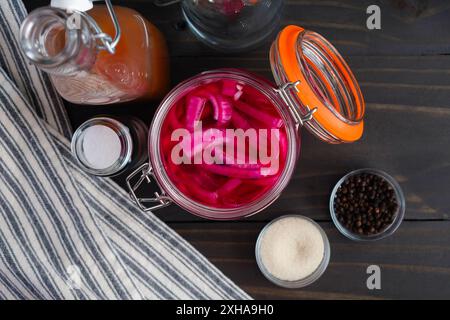 Barattolo di cipolle martellate direttamente dall'alto: Cipolla rossa a fette dai colori vivaci sottaceto in un barattolo muratore circondato da ingredienti Foto Stock