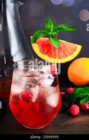Sangria di sakè guarnita con cara Orange Slice: Cocktail Fusion a base di sakè, arance, lamponi e more serviti su cubetti di ghiaccio Foto Stock