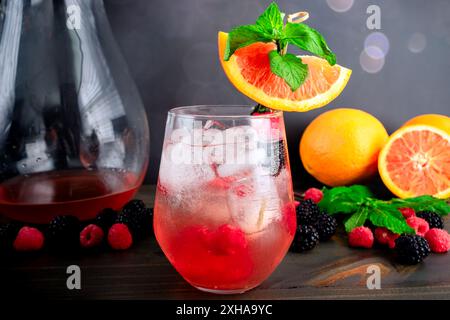 Sangria di sakè guarnita con cara Orange Slice: Cocktail Fusion a base di sakè, arance, lamponi e more serviti su cubetti di ghiaccio Foto Stock