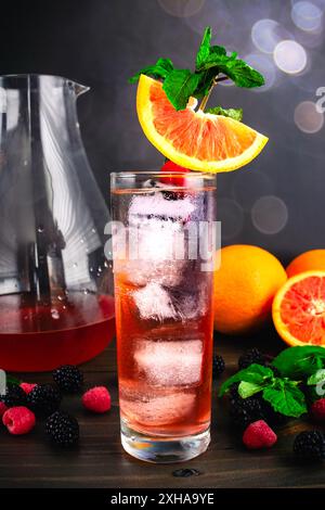 Sangria di sakè guarnita con cara Orange Slice: Cocktail Fusion a base di sakè, arance, lamponi e more serviti su cubetti di ghiaccio Foto Stock