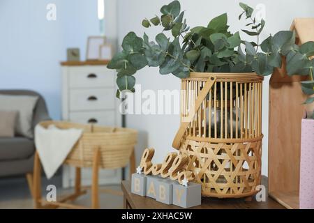 Cesto di vimini con bellissimi rami di eucalipto e frase Ciao Baby su tavolo di legno all'interno. Design degli interni Foto Stock