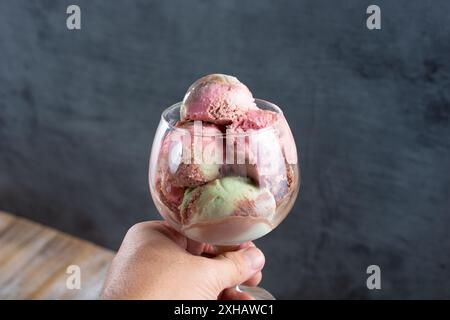 Vista di una mano che regge un bicchiere di gelato agli spumoni. Foto Stock