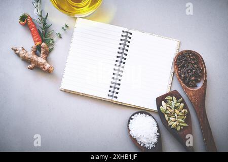 Ricetta, spezie e condimenti a tavola con libro, ispirazione o nuove idee per la tecnica di cottura per la cucina. Ricettario, istruzioni o ingrediente Foto Stock