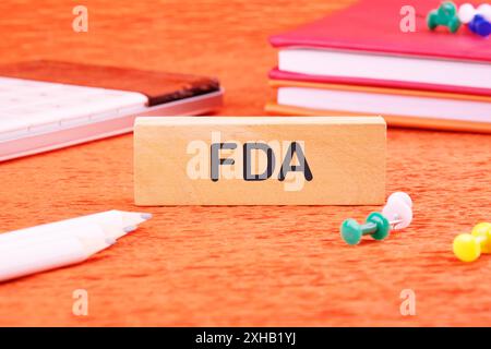 Simbolo FDA Food Drug Administration su blocchi di legno davanti a uno sfondo arancione Foto Stock