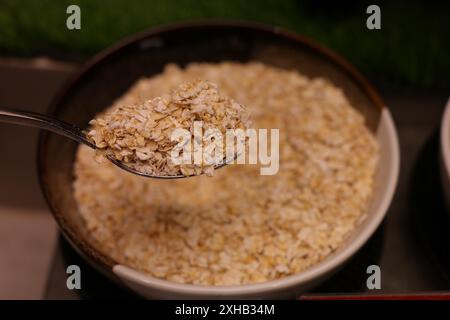 Primo piano di farina d'avena in un recipiente con cucchiaio Foto Stock