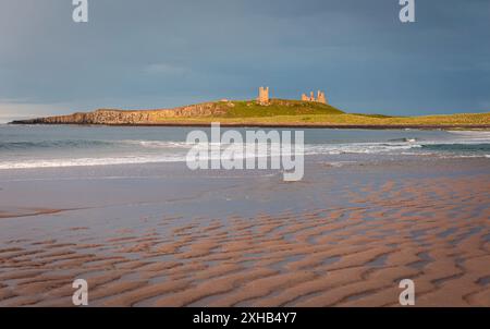 Evening golden hour catching the ruins of Dunstanburgh castle from Embleton bay on the Northumberland coast north east England UK Stock Photo