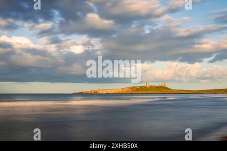 Ora d'oro serale per ammirare le rovine del castello di Dunstanburgh dalla baia di Embleton sulla costa del Northumberland, Inghilterra nord-orientale, Regno Unito Foto Stock