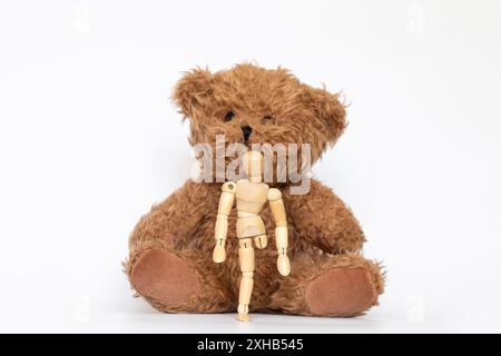 Uomo di legno senza una gamba e un orso su sfondo bianco, giocattoli per bambini Foto Stock