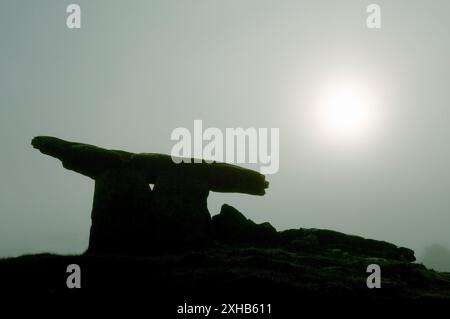 Poulnabrone tomba preistorica a dolmen sagomata contro il sole della luna nella nebbia sull'altopiano calcareo di Burren, contea di Clare, Irlanda Foto Stock