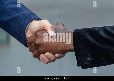 Vista ravvicinata di una stretta di mano tra un uomo d'affari afroamericano e un uomo d'affari caucasico, simboleggiando la diversità e la collaborazione in un corporat Foto Stock