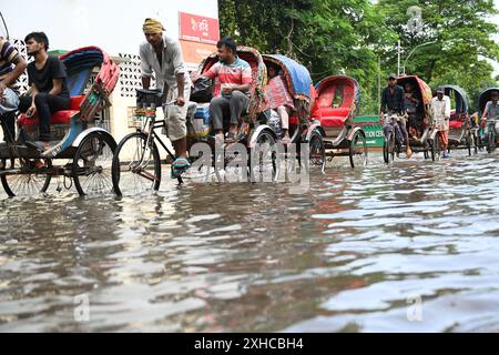 Persone e veicoli che cercano di muoversi attraverso la strada bagnata di Dacca, Bangladesh, il 26 luglio 2024 Foto Stock
