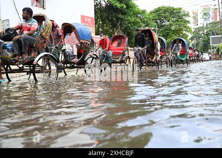 Persone e veicoli che cercano di muoversi attraverso la strada bagnata di Dacca, Bangladesh, il 26 luglio 2024 Foto Stock