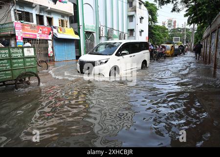 Persone e veicoli che cercano di muoversi attraverso la strada bagnata di Dacca, Bangladesh, il 26 luglio 2024 Foto Stock