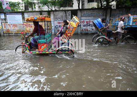 Persone e veicoli che cercano di muoversi attraverso la strada bagnata di Dacca, Bangladesh, il 26 luglio 2024 Foto Stock