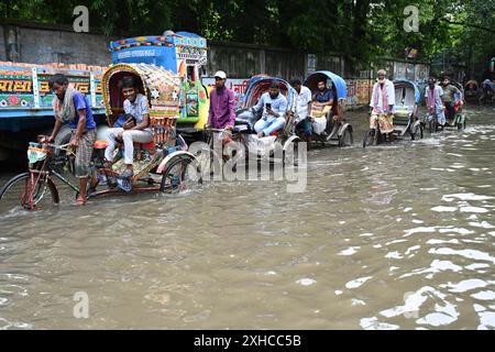 Persone e veicoli che cercano di muoversi attraverso la strada bagnata di Dacca, Bangladesh, il 26 luglio 2024 Foto Stock