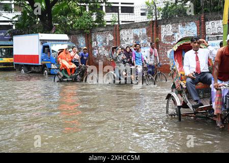 Persone e veicoli che cercano di muoversi attraverso la strada bagnata di Dacca, Bangladesh, il 26 luglio 2024 Foto Stock