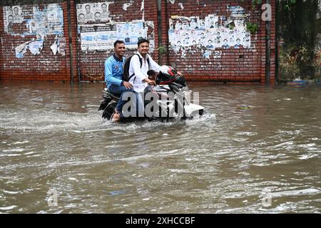 Persone e veicoli che cercano di muoversi attraverso la strada bagnata di Dacca, Bangladesh, il 26 luglio 2024 Foto Stock