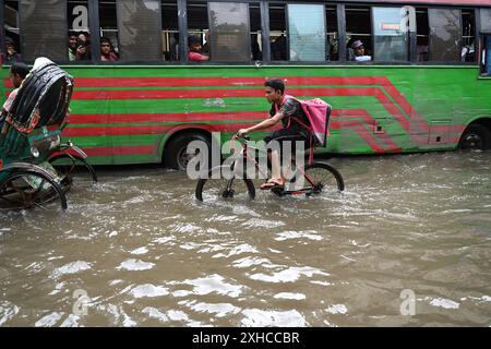 Persone e veicoli che cercano di muoversi attraverso la strada bagnata di Dacca, Bangladesh, il 26 luglio 2024 Foto Stock