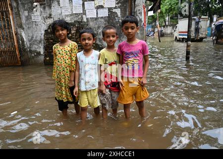 Persone e veicoli che cercano di muoversi attraverso la strada bagnata di Dacca, Bangladesh, il 26 luglio 2024 Foto Stock