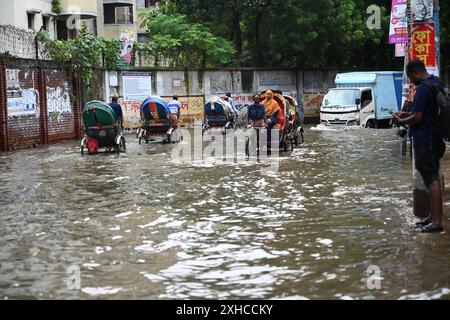 Persone e veicoli che cercano di muoversi attraverso la strada bagnata di Dacca, Bangladesh, il 26 luglio 2024 Foto Stock