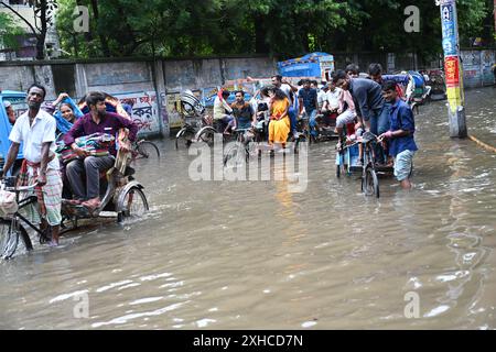 Persone e veicoli che cercano di muoversi attraverso la strada bagnata di Dacca, Bangladesh, il 26 luglio 2024 Foto Stock
