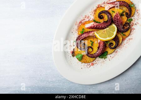 Polpo con patate e spezie, su un piatto leggero, vista dall'alto, niente persone, fatti in casa, primo piano Foto Stock