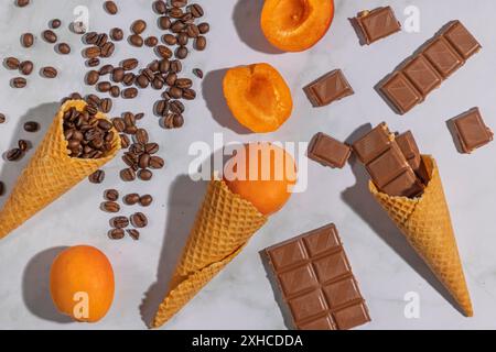 Coni di gelato con chicchi di caffè, albicocche e cioccolato su sfondo di marmo Foto Stock