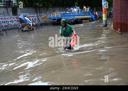Persone e veicoli che cercano di muoversi attraverso la strada bagnata di Dacca, Bangladesh, il 26 luglio 2024 Foto Stock