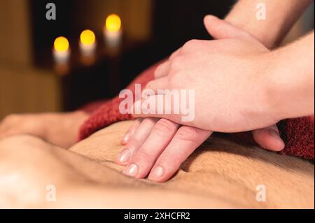 Il massaggiatore maschile da vicino massaggia lo stomaco del cliente mentre fa un massaggio dell'intestino e dell'area addominale a un atleta maschile Foto Stock