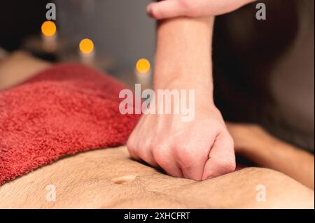 Il massaggiatore maschile da vicino massaggia lo stomaco del cliente mentre fa un massaggio dell'intestino e dell'area addominale a un atleta maschile Foto Stock