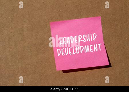 Messaggio di sviluppo della leadership scritto su carta rosa con sfondo in cartone. Simbolo dello sviluppo della leadership concettuale. Copia spazio. Foto Stock