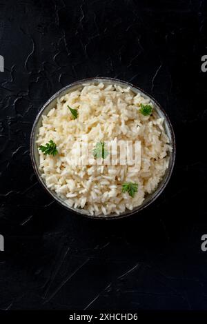 Riso bianco, cotto, con prezzemolo, colpo d'alto su sfondo nero con un posto per il testo Foto Stock