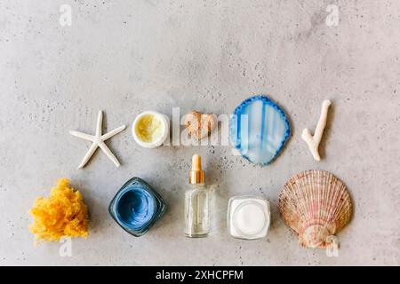 Vista dall'alto di vari prodotti cosmetici in vasi disposti su tavolo con conchiglie e pietra minerale Foto Stock