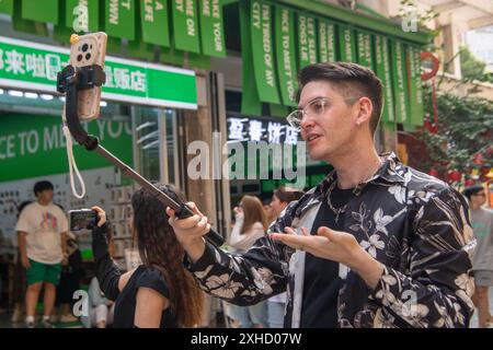 (240713) -- CHONGQING, 13 luglio 2024 (Xinhua) -- Ilia Anfilatov prende video in un parco culturale nel distretto di Yuzhong, nella municipalità di Chongqing della Cina sud-occidentale, 12 luglio 2024. Gli studenti internazionali Ilia Anfilatov dalla Russia e Syyra Alee dal Pakistan studiano alla Southwest University di Chongqing da oltre un anno. Nel loro tempo libero, amano passeggiare per la città e condividere le loro esperienze sui social media. Grazie alla loro condivisione, molti dei loro amici e famiglie sono attratti dallo splendido paesaggio e dalla diversa cultura della Cina e hanno in programma di imbarcarsi in un viaggio a CH Foto Stock