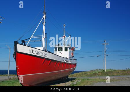 Barca rossa a terra accanto a una strada costiera sotto un cielo azzurro, Gaspesie, fiume San Lorenzo, Quebec, Canada Foto Stock