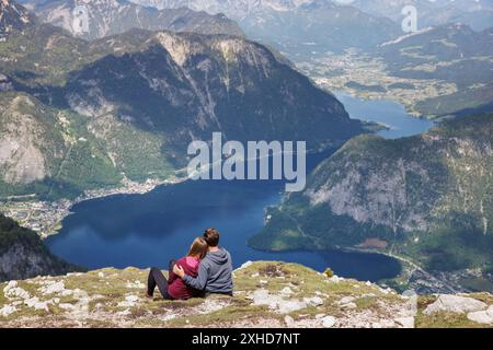 Obertraun, Austria. 20 maggio 2024. Il 20.05.2024, una coppia siede sulla cima del Krippenstein, una montagna alta 2108 metri sul bordo settentrionale dei Monti Dachstein nel comune di Obertraun nell'alta Austria (sterreich) e si affaccia sul lago Hallstatt e sul paesaggio montano circostante. Il villaggio di Hallstatt si trova sulla riva sinistra del lago di montagna, circondato da una vista panoramica sulle montagne dell'alta Austria Salzkammergut. Crediti: Matthias Balk/dpa/Alamy Live News Foto Stock