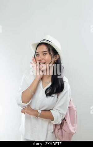 Ritratto di una giovane donna asiatica che indossa un cappello di paglia, tutti vestiti bianchi indicano che le vacanze sono qui, pubblicità Foto Stock